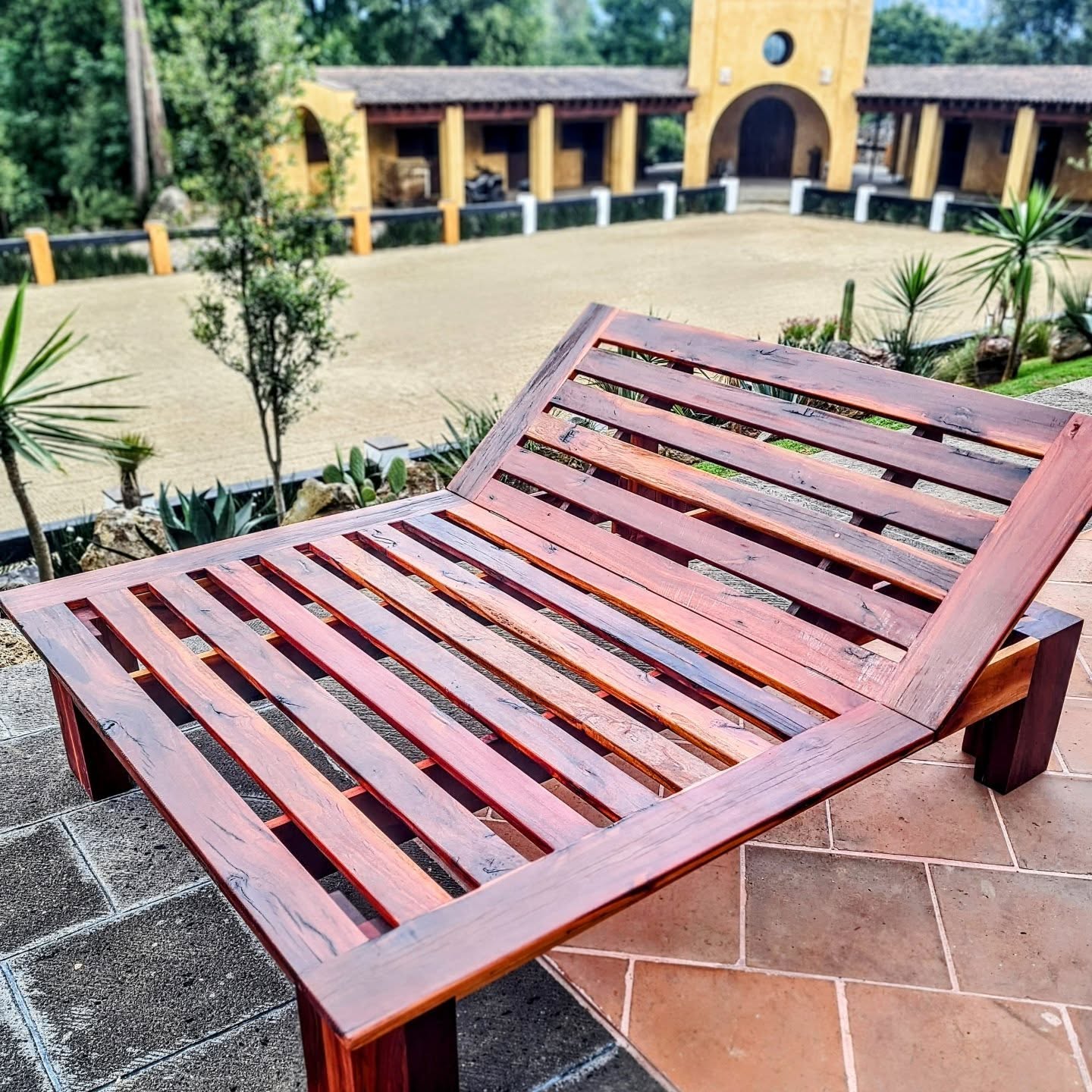 Outdoor slatted wood chaise lounge on a hacienda terrace