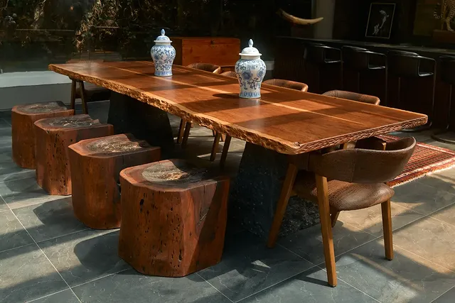 Long live-edge dining table with stone and wood pedestals, tree-stump stools